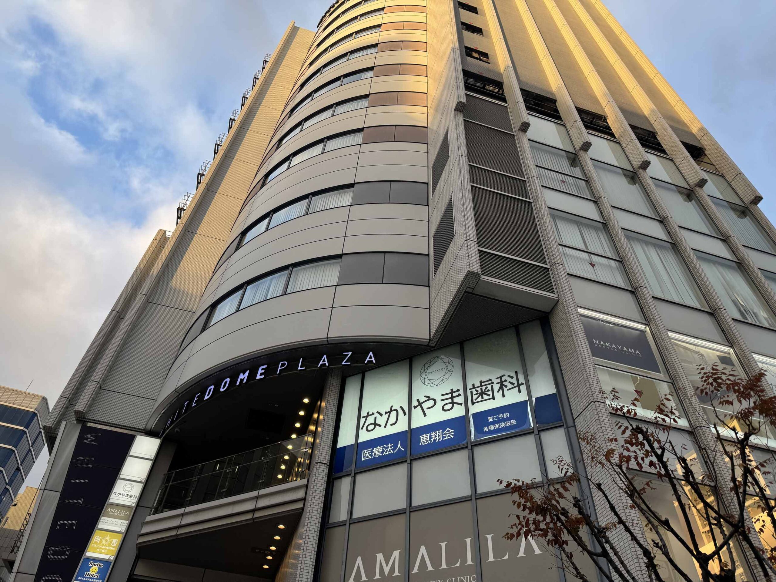 WHITE DOME PLAZA大樓外觀仰角拍攝，大阪微笑飯店位在這棟建築內，旁邊是中山齒科與AMALILA美容診所