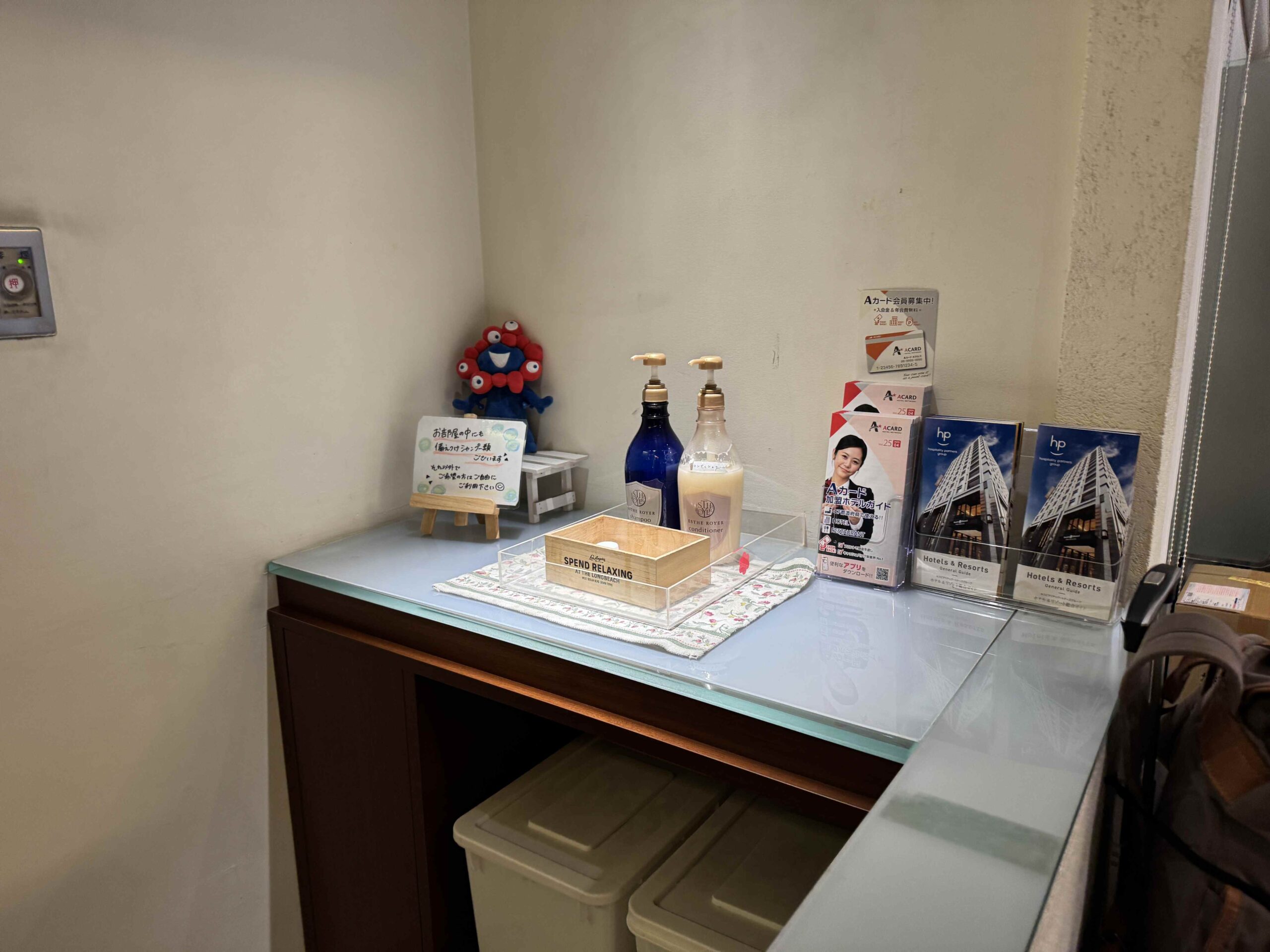 飯店一樓Amenity bar放置免費備品，含洗髮乳潤髮乳試用瓶、Smile Hotel吉祥物擺設與Hotels & Resorts品牌簡介