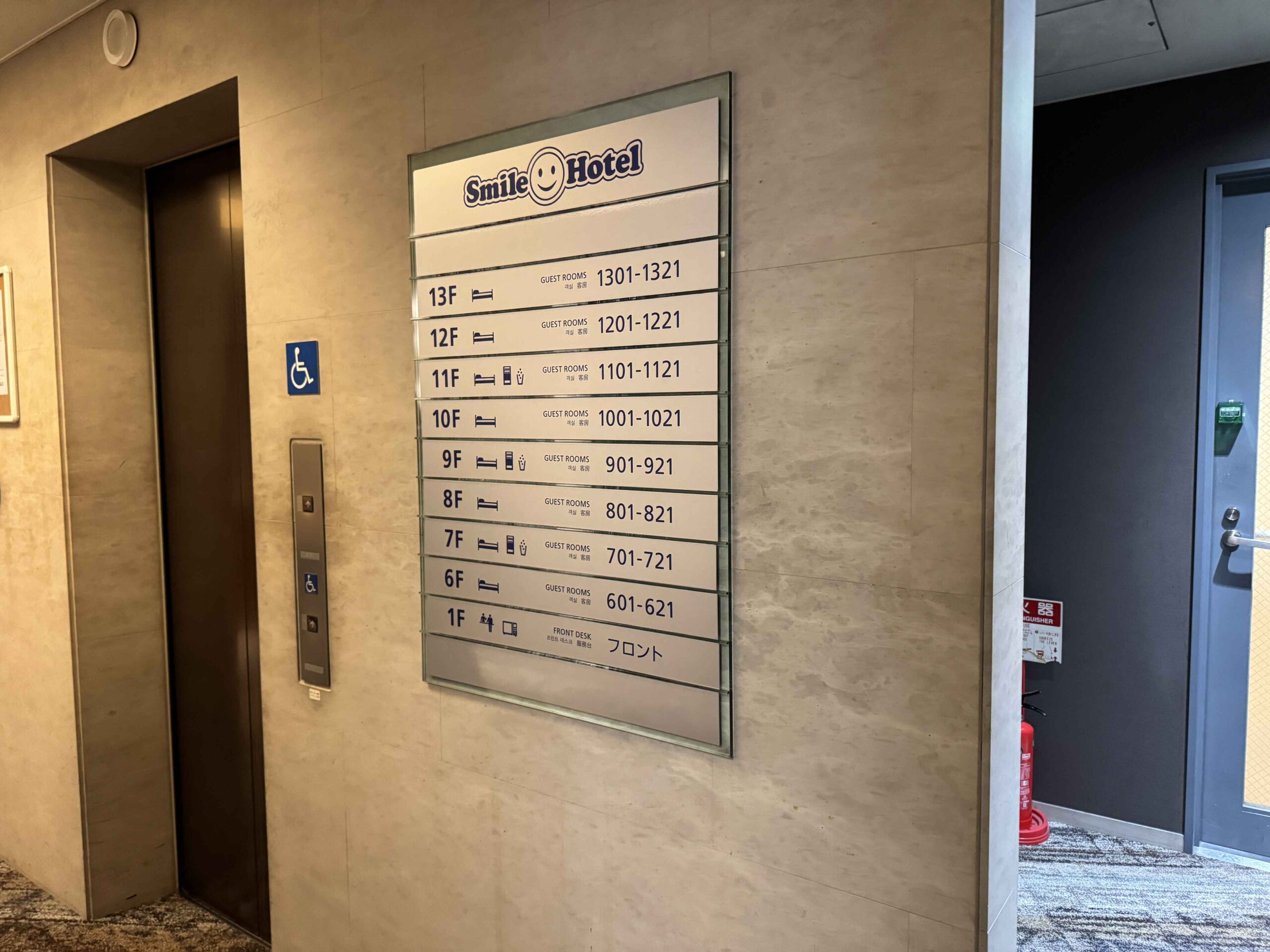 飯店電梯外樓層配置牌，Smile Hotel品牌logo與1F前台、6F至13F客房分區指引牌