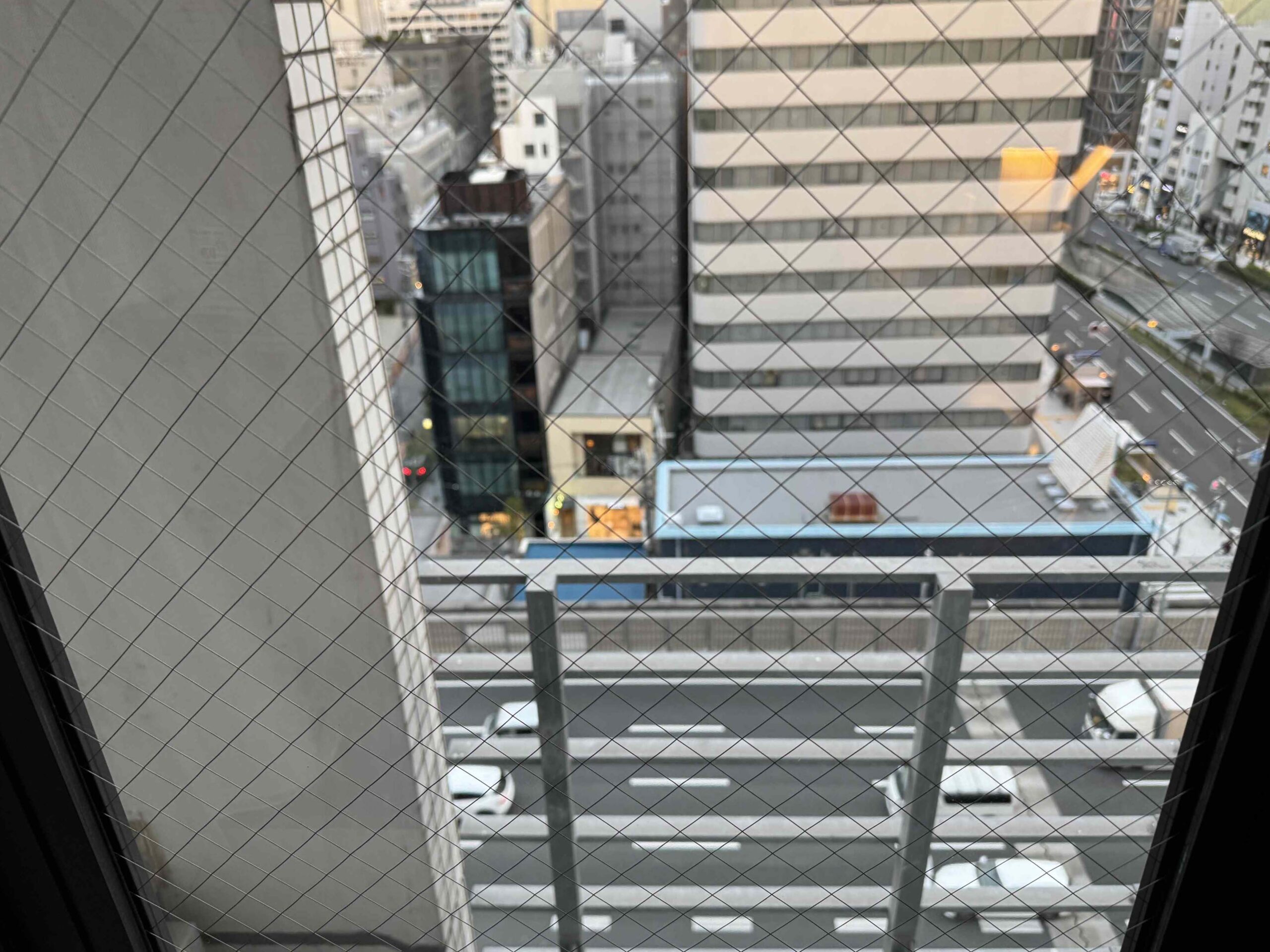 大阪市區窗景，從12樓往下俯瞰辦公大樓街區，玻璃外有防墜網格