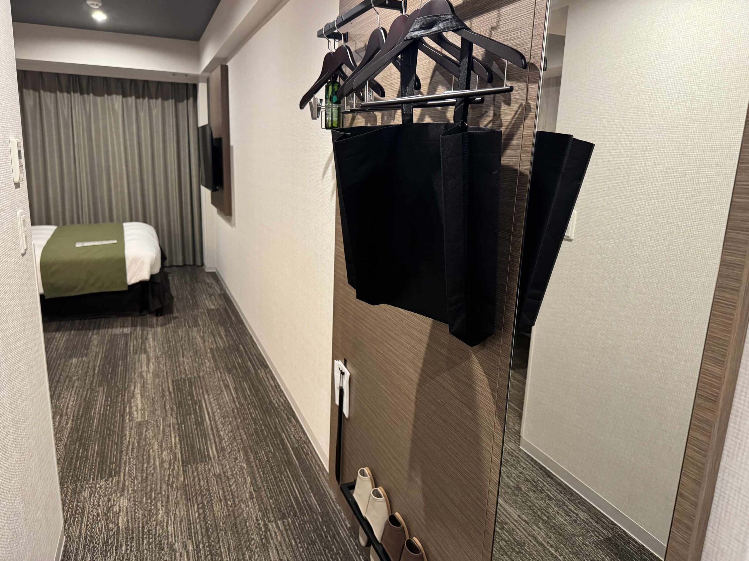 進房後的玄關衣架區，黑色購物袋掛上全身鏡延伸至床區的房型走道