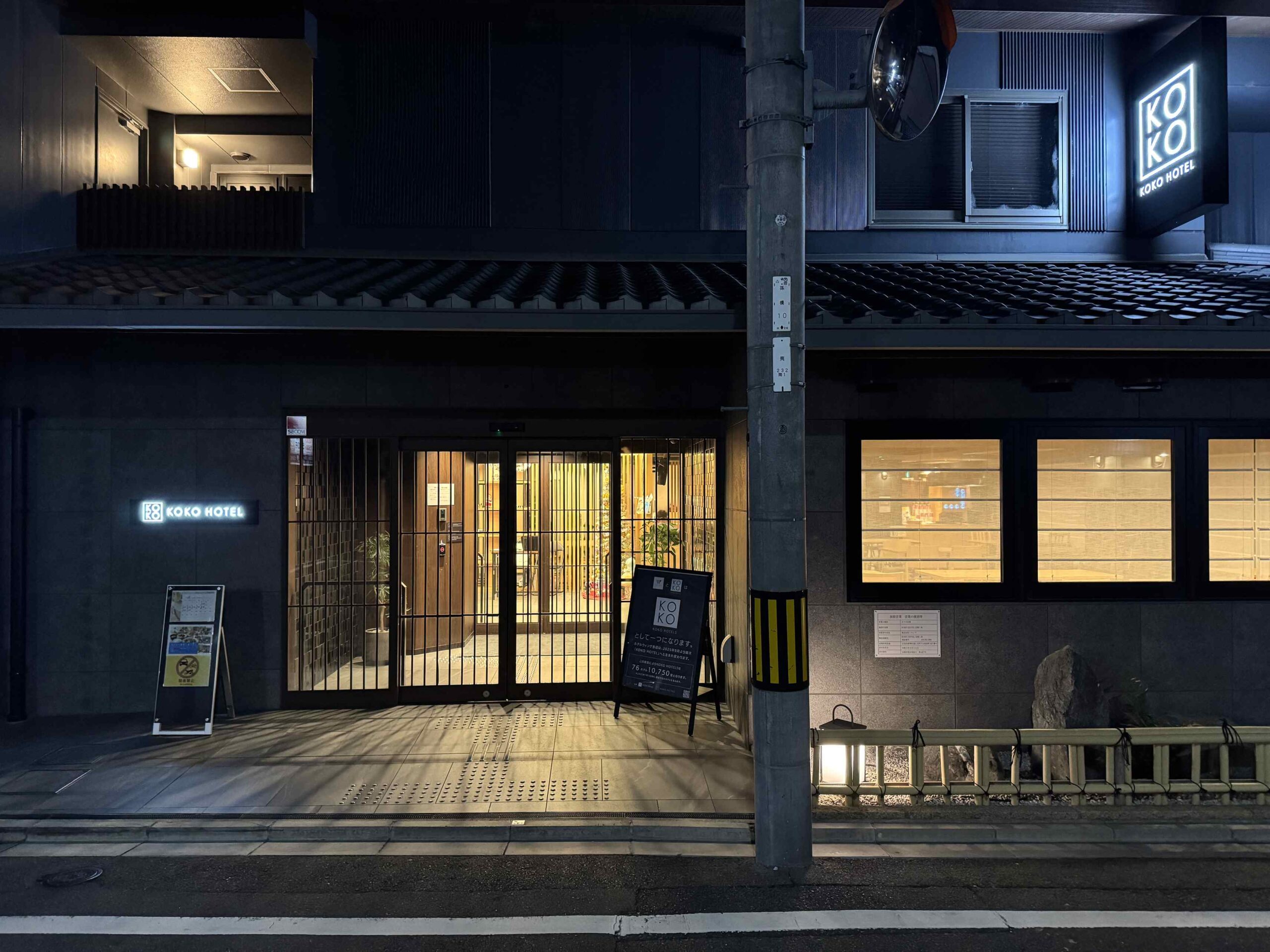 KOKO HOTEL京都三條飯店正面入口夜景，黑色木格柵建築外觀與雙開玻璃自動門